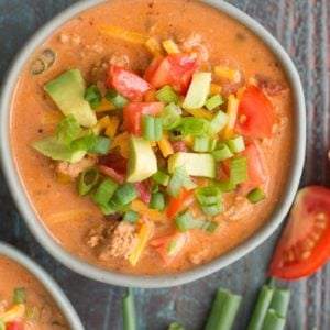 overhead shot of keto taco soup garnished with avocado, tomato, cheese, and green onions