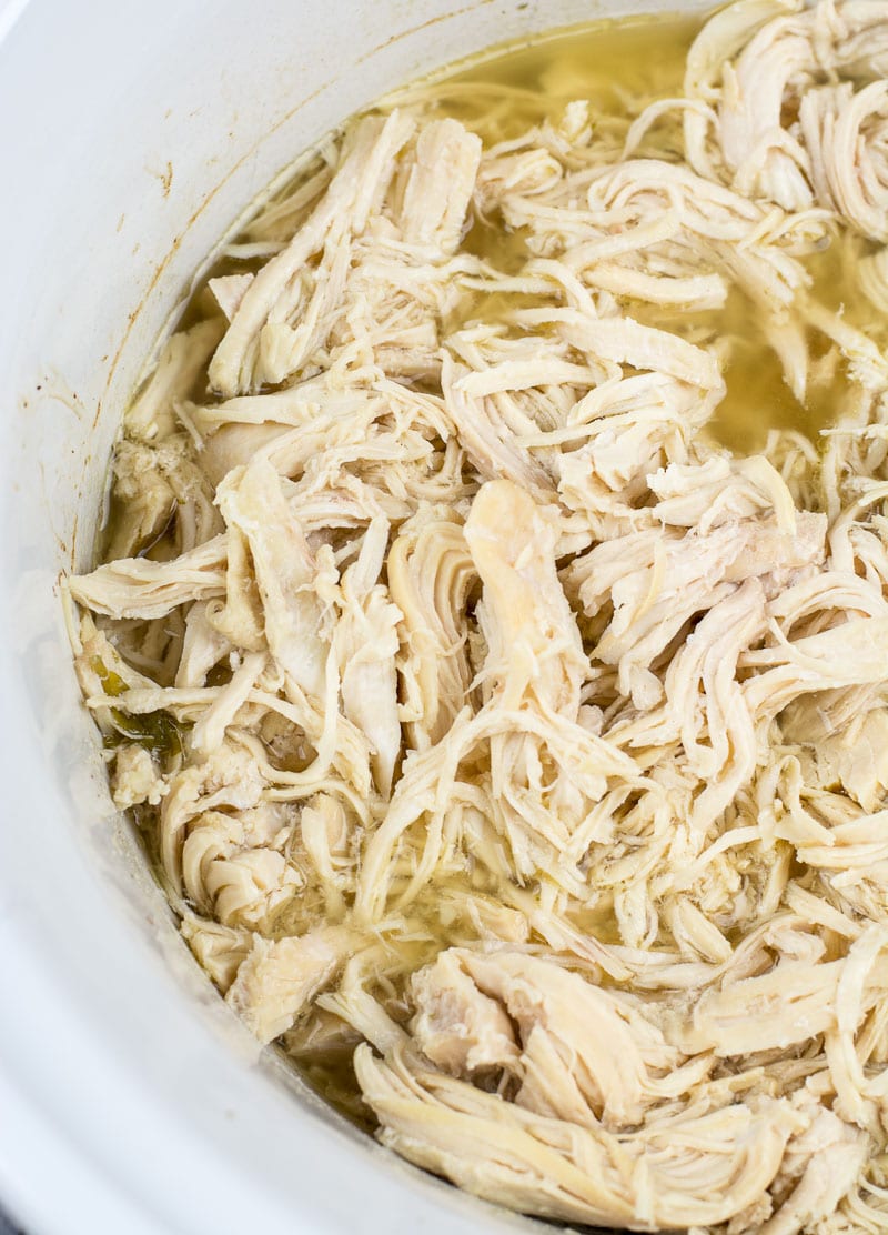 Close up of slow cooker shredded chicken in its juices. 