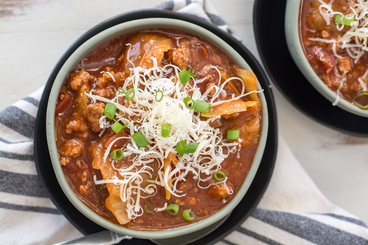 overhead view of a bowl of keto cabbage soup garnished with green onions and shredded cheese