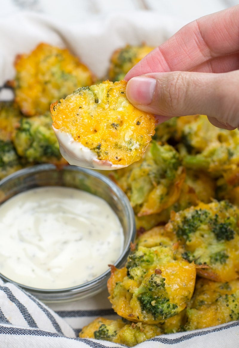 a keto broccoli and cheese bite being held above a dish of ranch dressing 