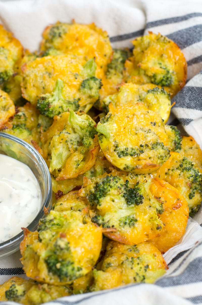 a pile of cheesy broccoli bites in a striped towel next to a small dish of ranch