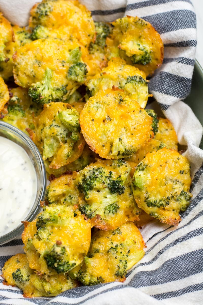 a pile of cheesy broccoli bites in a striped towel next to a small dish of ranch