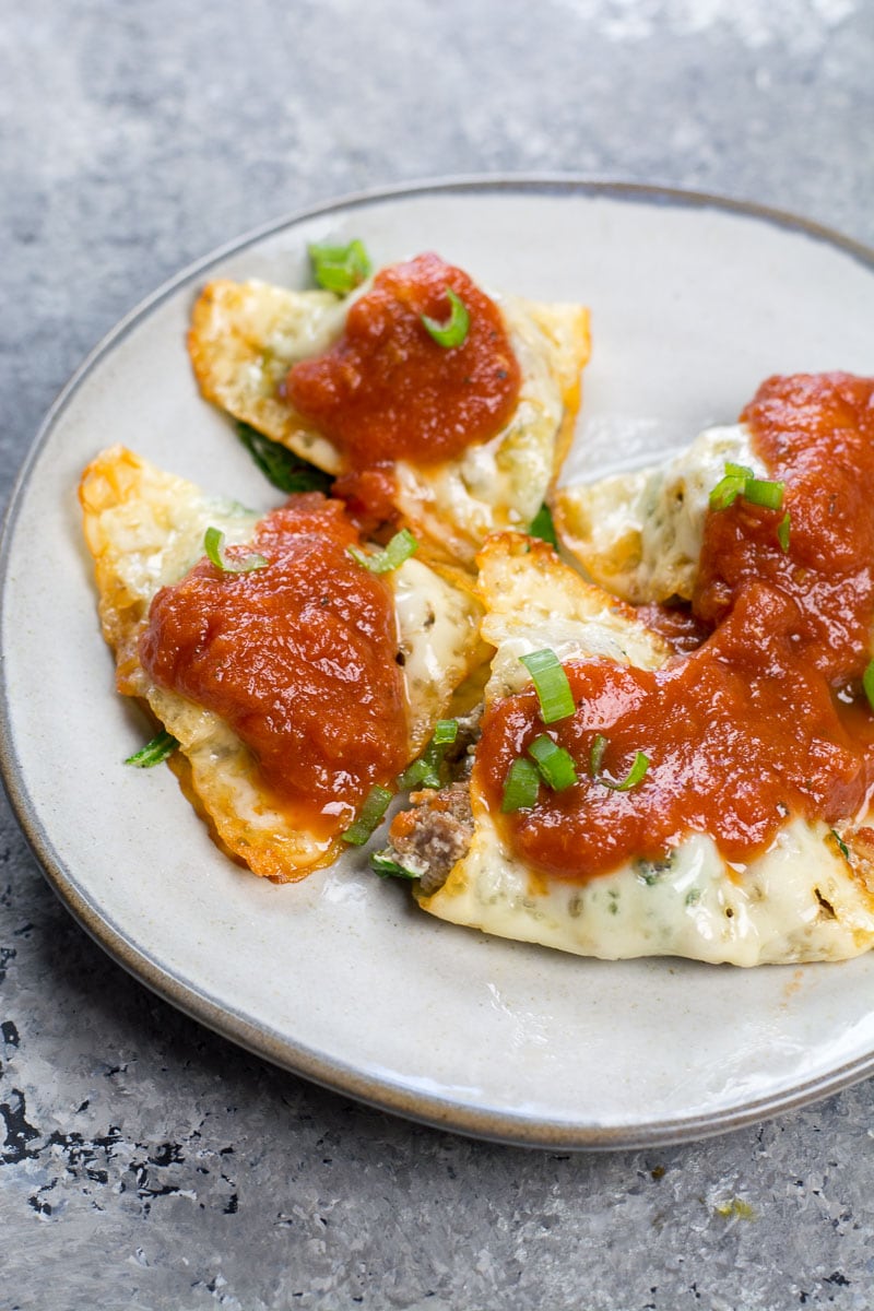 A white plate with four pieces of keto ravioli on it. 