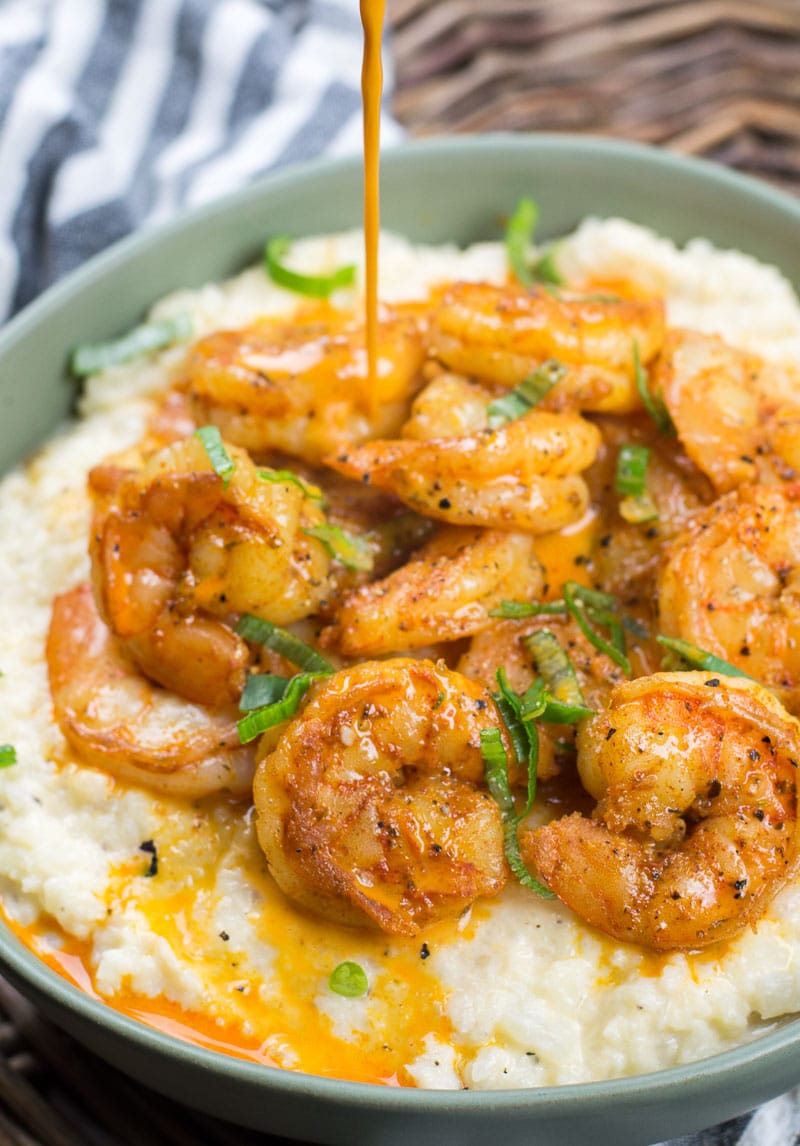 butter sauce being poured over low carb shrimp and grits in a green bowl 