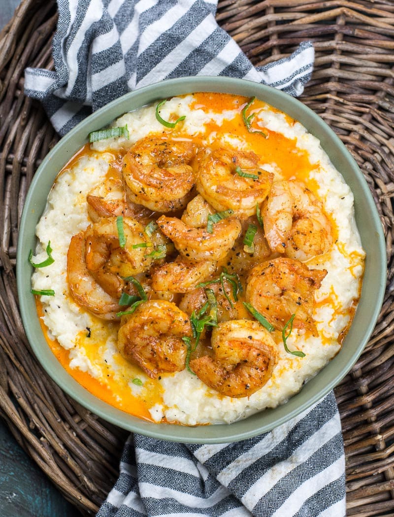 overhead view of keto shrimp and grits in a green bowl on a wicker basket