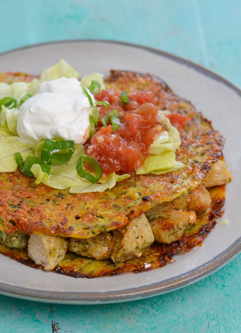 a keto tortilla stuffed with chicken and topped with salsa, sour cream, and lettuce 