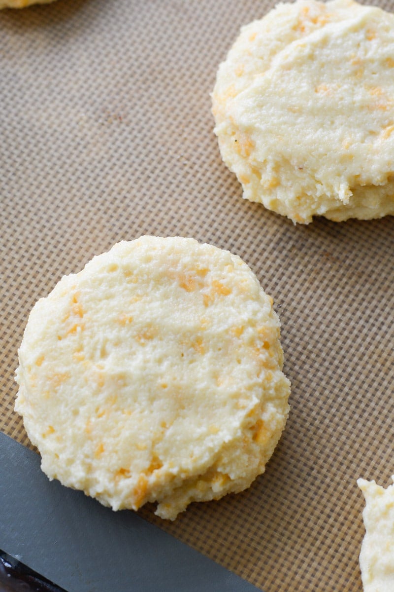 Almond flour keto biscuit dough is cut and placed on a lined baking sheet