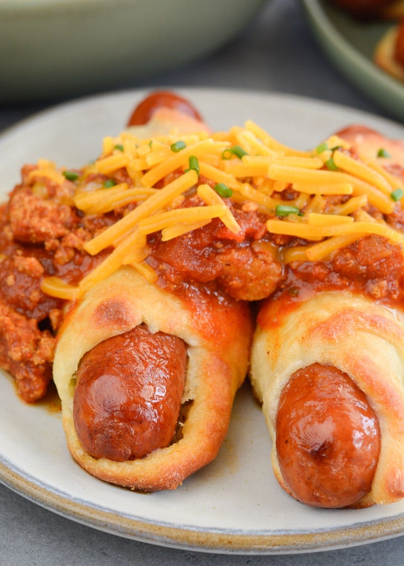 These Keto Chili Cheese Dogs have everything you love about this classic, without the carbs! Easy, low carb, gluten free pigs in a blanket are smothered with keto chili and shredded cheddar cheese! For about 5 net carbs per serving this is a low carb recipe you will love! 