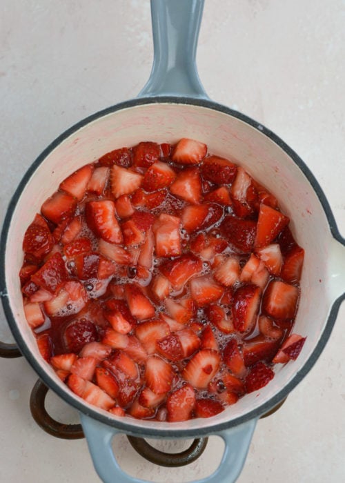 strawberries cooking down into a thick sauce in a sauce pan
