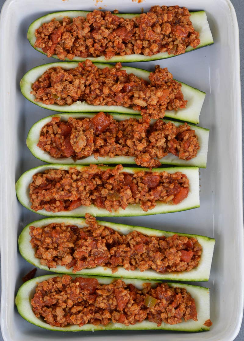 Warning! These Chili Cheese Stuffed Zucchini Boats are super addictive! Fresh zucchini is stuffed with keto chili and topped with sharp cheddar cheese!