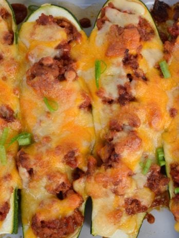 Warning! These Chili Cheese Stuffed Zucchini Boats are super addictive! Fresh zucchini is stuffed with keto chili and topped with sharp cheddar cheese!