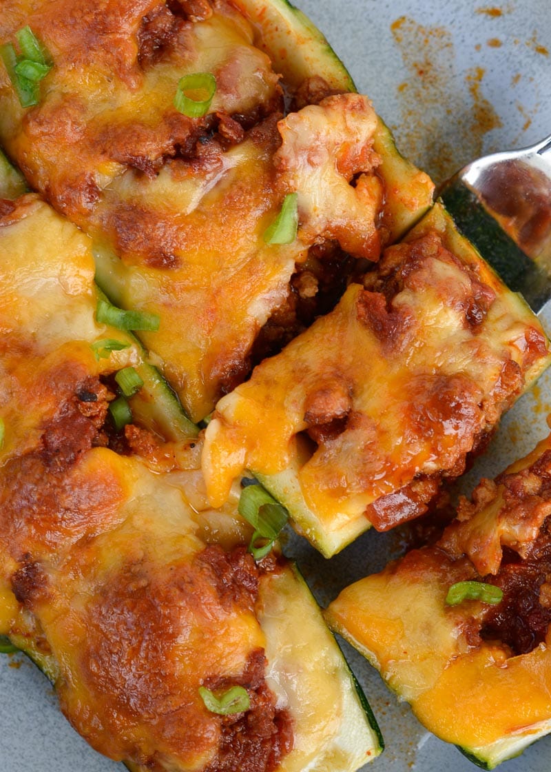 Warning! These Chili Cheese Stuffed Zucchini Boats are super addictive! Fresh zucchini is stuffed with keto chili and topped with sharp cheddar cheese!