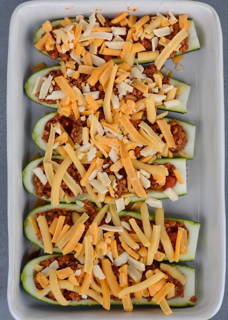 Warning! These Chili Cheese Stuffed Zucchini Boats are super addictive! Fresh zucchini is stuffed with keto chili and topped with sharp cheddar cheese!