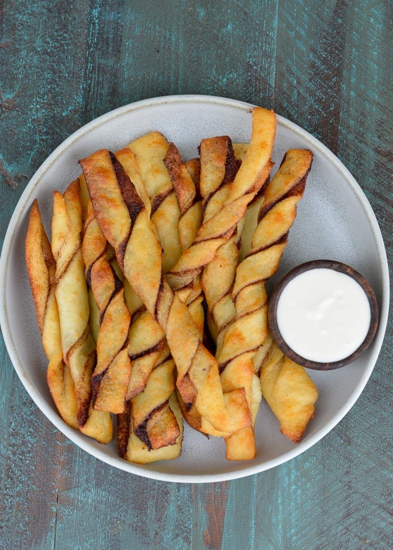 These easy Keto Cinnamon Twists have a delicious keto cream cheese dipping sauce for the best gluten free + keto snack! Enjoy two twists and frosting for just 3 net carbs!