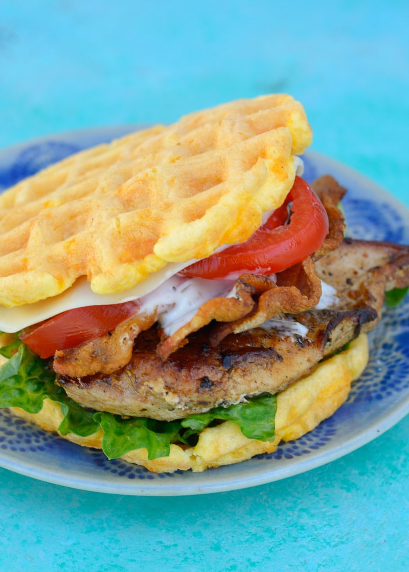 grilled chicken with bacon, ranch, tomato, and lettuce between two chaffles on a blue pattern plate