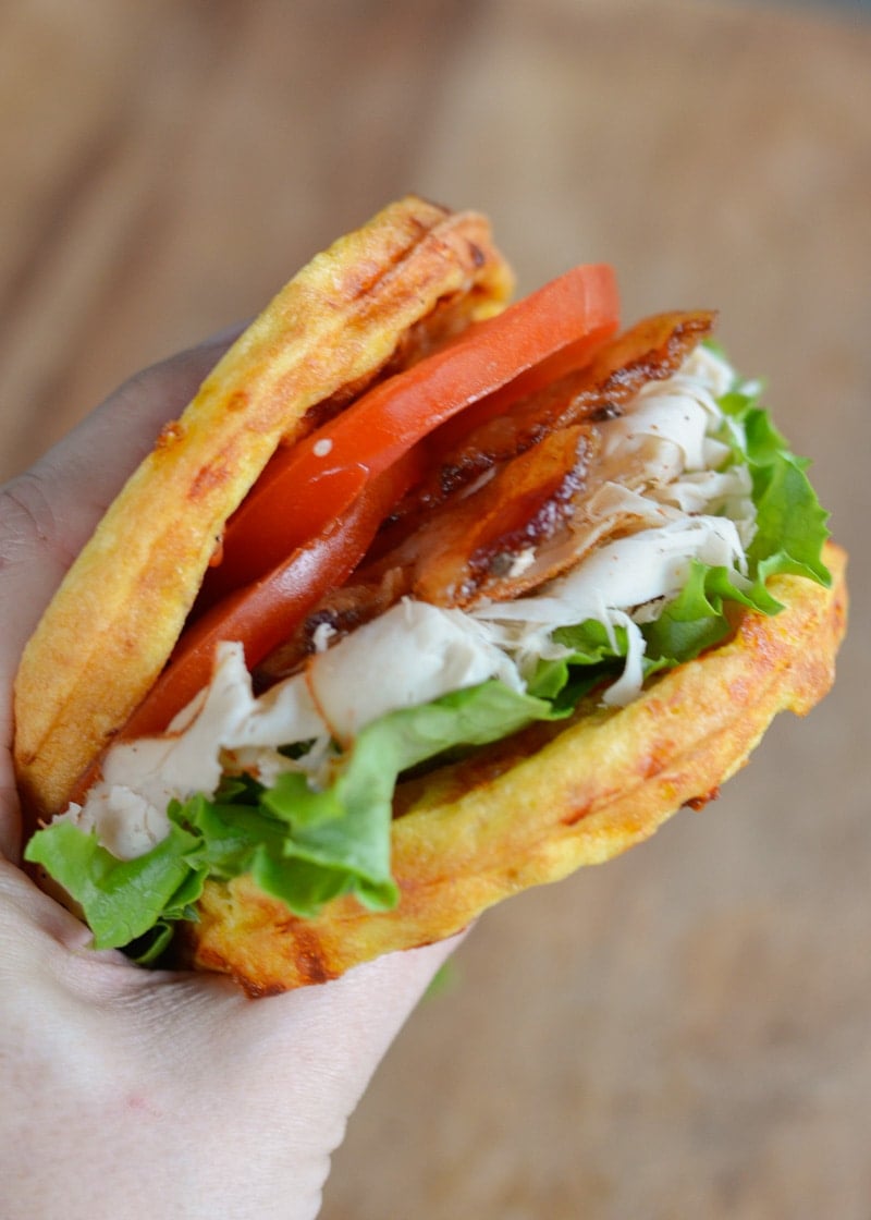 deli turkey, lettuce, bacon, and tomato between two chaffles, being held by a hand