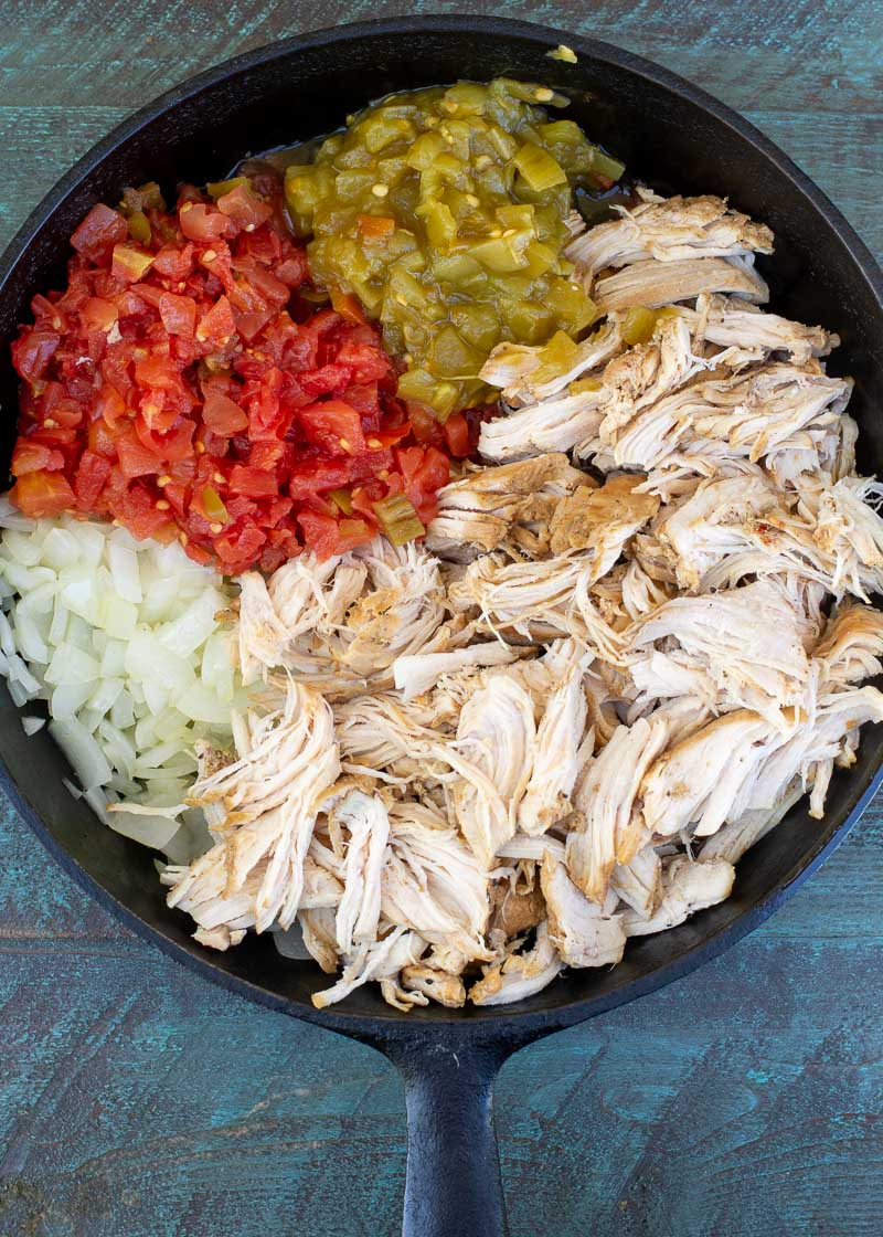 an overhead shot of a skillet with chicken, tomatoes and vegetables