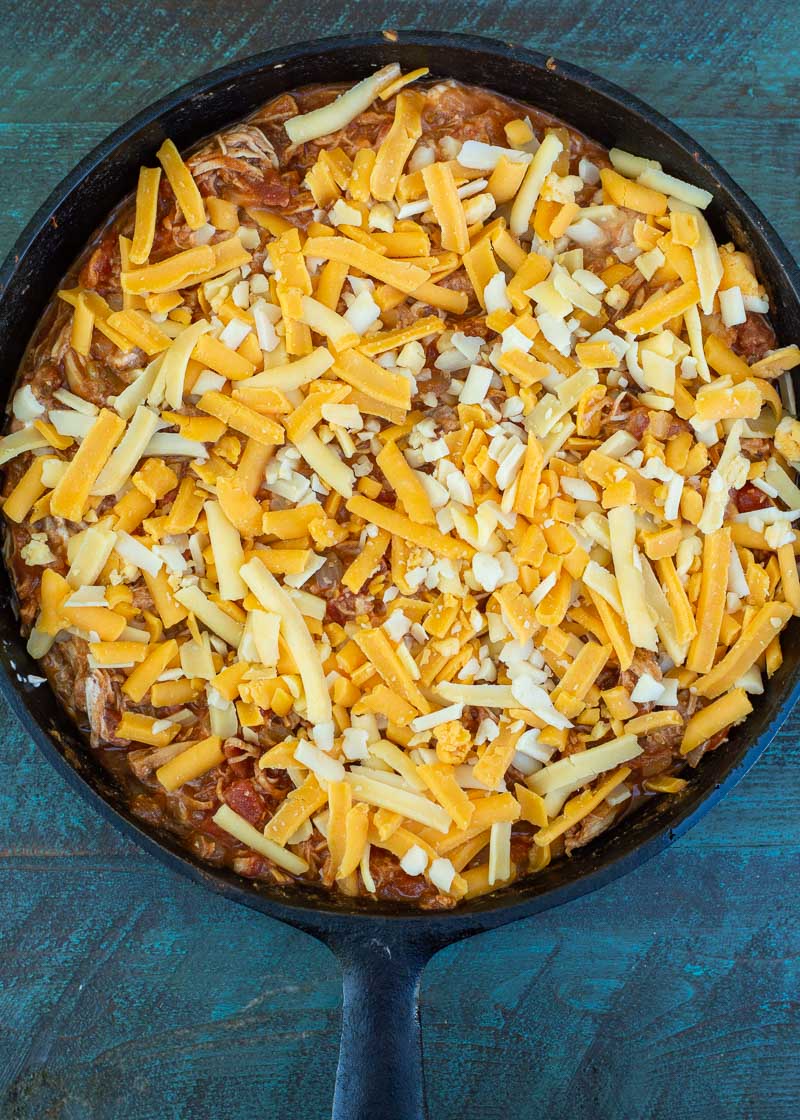 enchilada filling and shredded cheese in a skillet