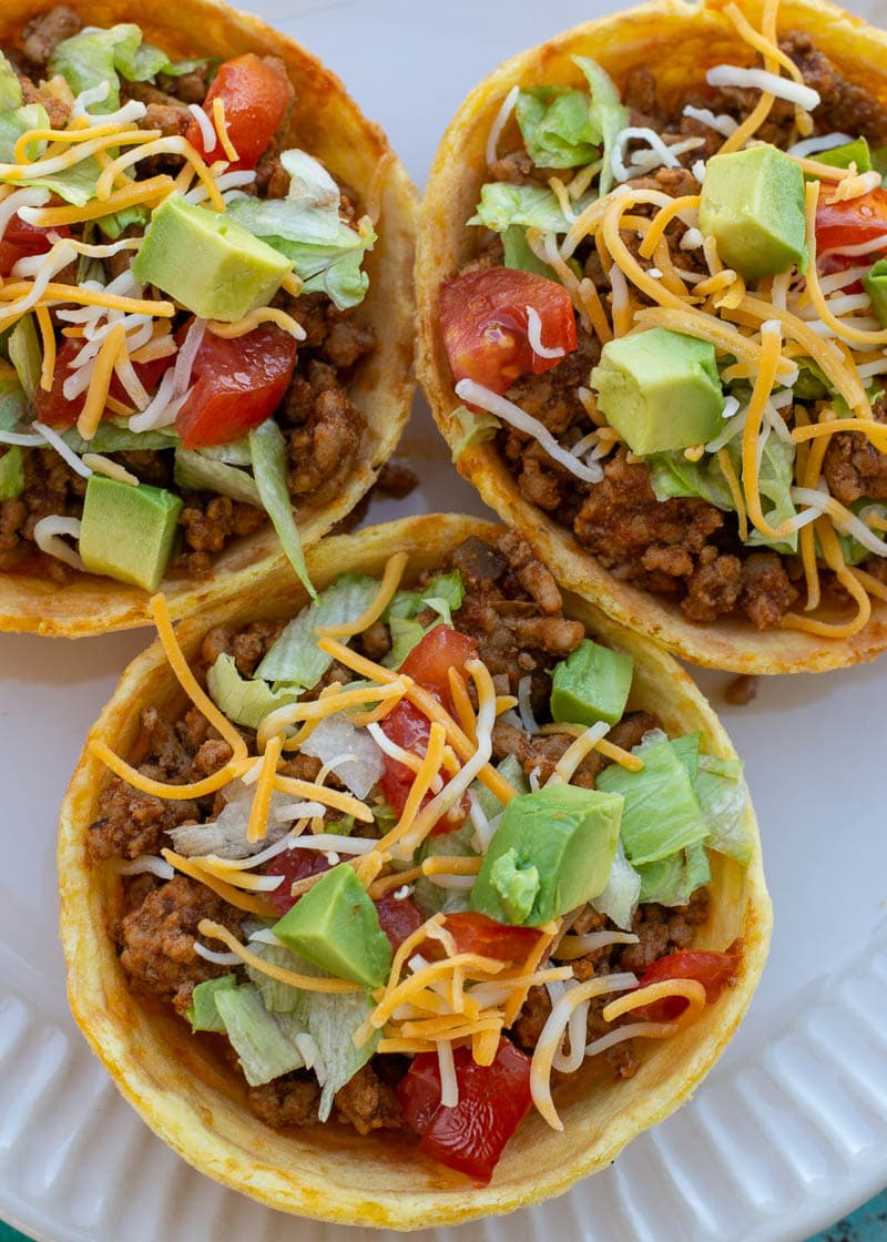 This Taco Chaffle Bowl is the perfect keto version of your favorite taco salad! Seasoned taco meat, cheese, lettuce and sour cream are combined in a crispy Chaffle Bowl for less than 3 net carbs!