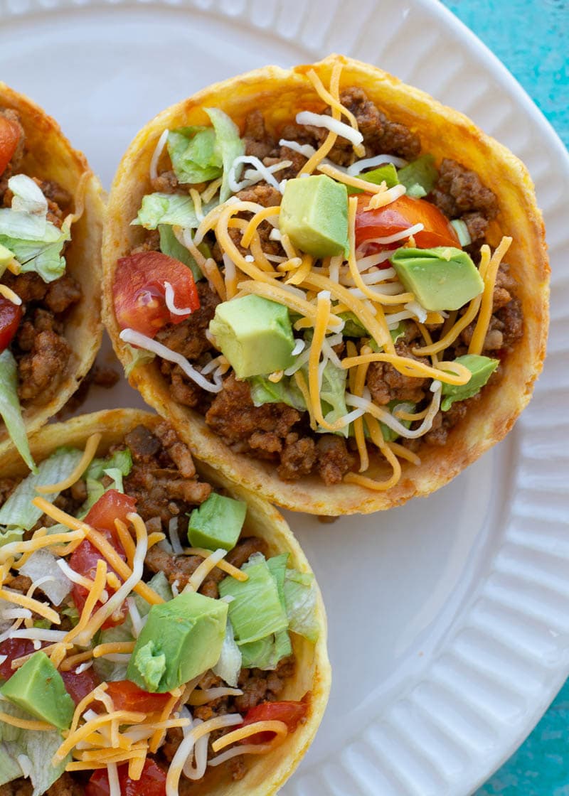 This Taco Chaffle Bowl is the perfect keto version of your favorite taco salad! Seasoned taco meat, cheese, lettuce and sour cream are combined in a crispy Chaffle Bowl for less than 3 net carbs!