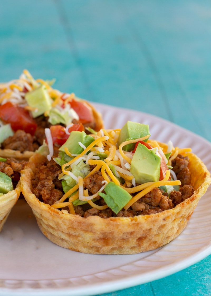 This Taco Chaffle Bowl is the perfect keto version of your favorite taco salad! Seasoned taco meat, cheese, lettuce and sour cream are combined in a crispy Chaffle Bowl for less than 3 net carbs!