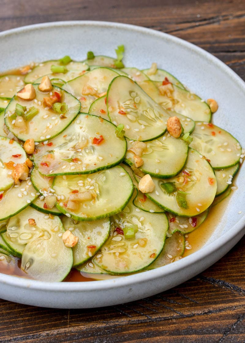 easy asian cucumber salad on a white speckled bowl and wooden background