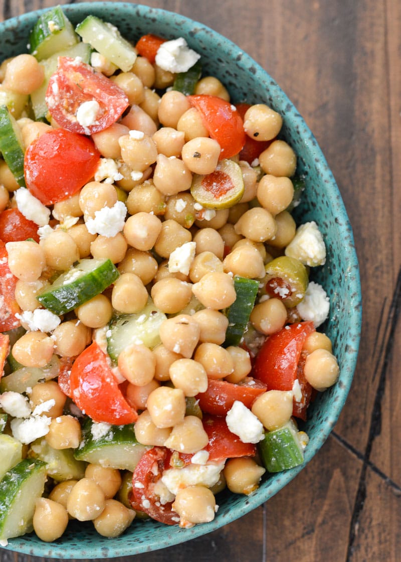 cucumber chickpea salad with tomatoes and feta in a green speckled bowl