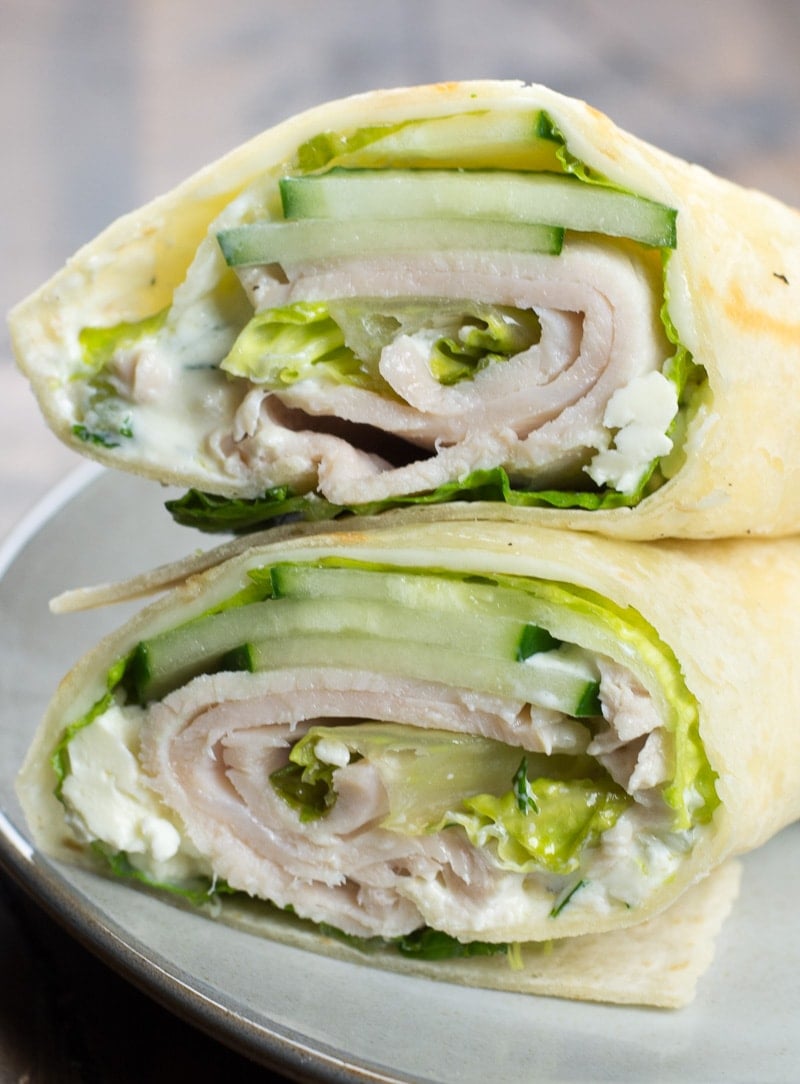 greek turkey and cucumber wrap sliced in half on a white plate