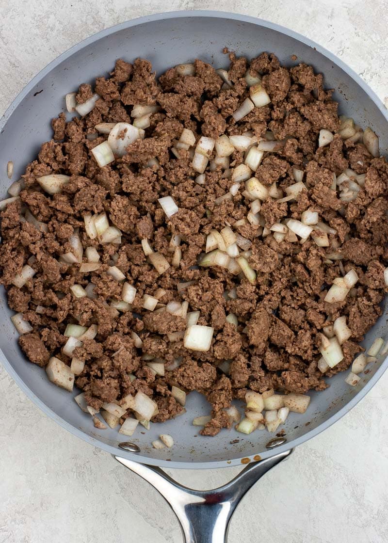 ground beef and onions browning in a pan