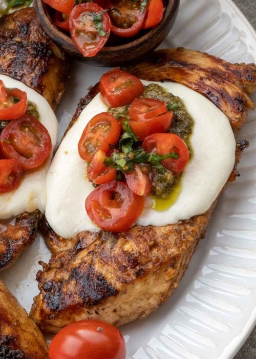 This Chicken Margherita recipe is full of fresh flavors! Balsamic Grilled Chicken is topped with fresh mozzarella, creamy pesto, and a bright tomato basil salad! 