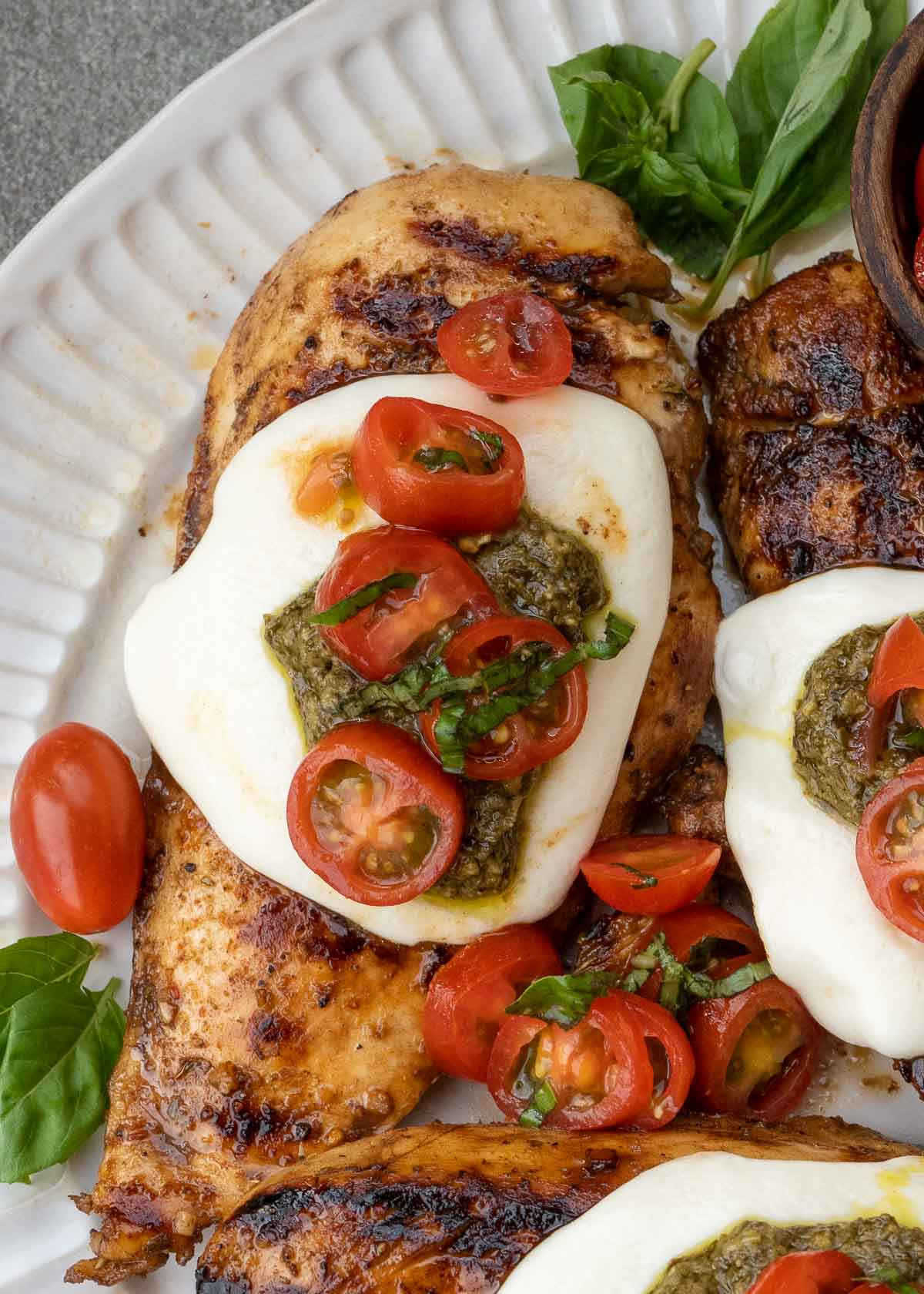 This Chicken Margherita recipe is full of fresh flavors! Balsamic Grilled Chicken is topped with fresh mozzarella, creamy pesto, and a bright tomato basil salad! 