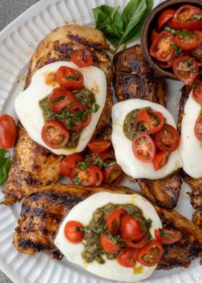 This Chicken Margherita recipe is full of fresh flavors! Balsamic Grilled Chicken is topped with fresh mozzarella, creamy pesto, and a bright tomato basil salad!