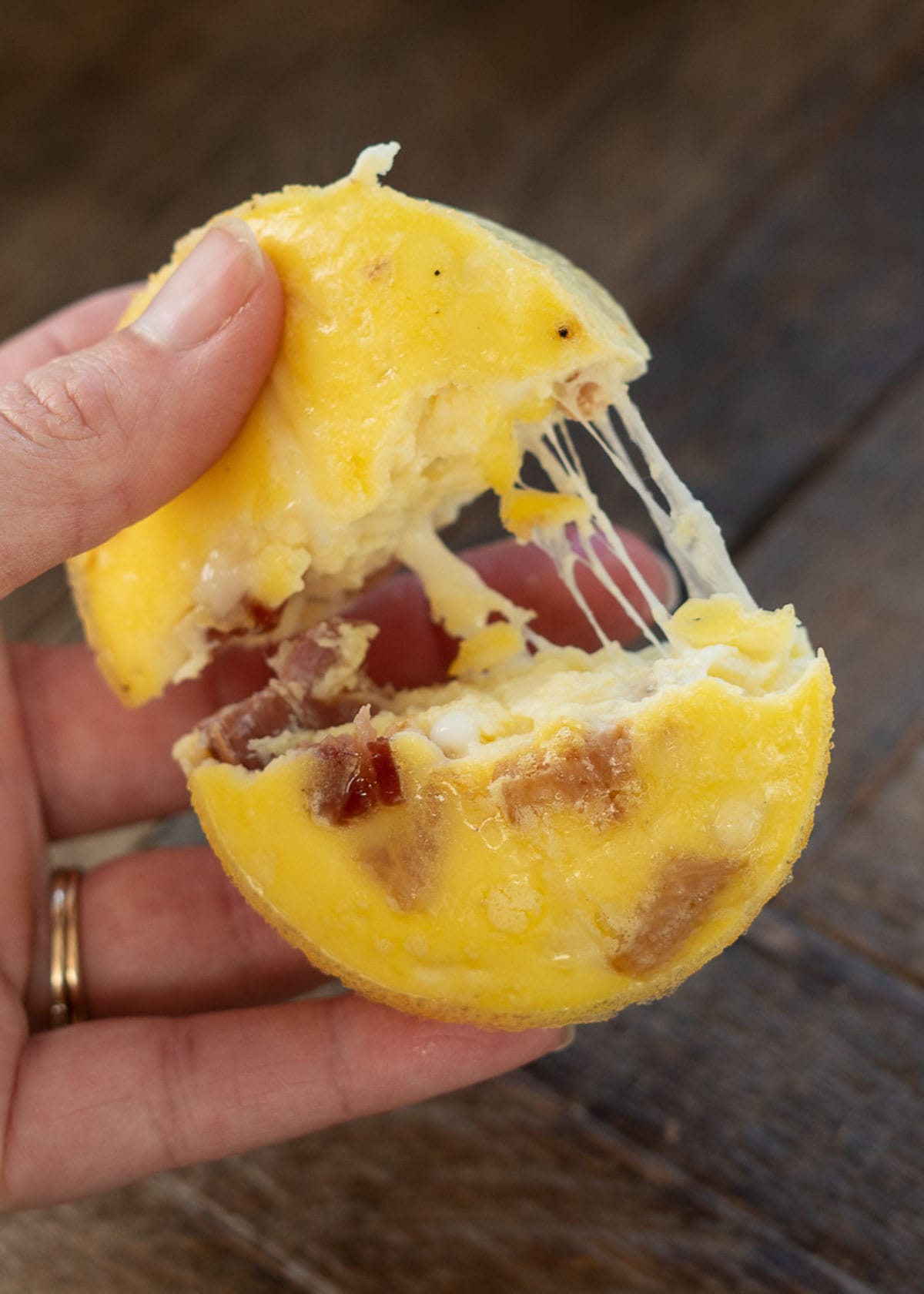A hand pulling apart a bacon egg bite