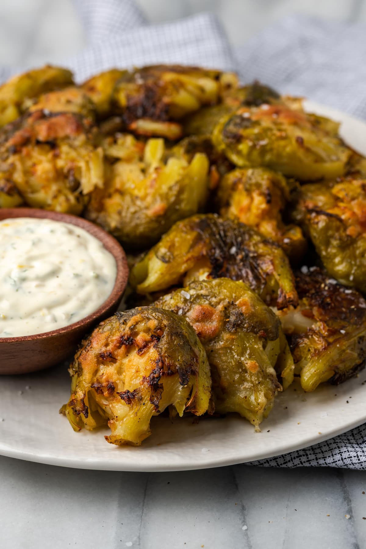Crispy smashed Brussels sprouts on plate with bowl of lemon aioli