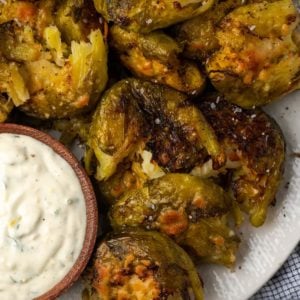 Overhead view of smashed Brussels sprouts on plate with bowl of lemon aioli