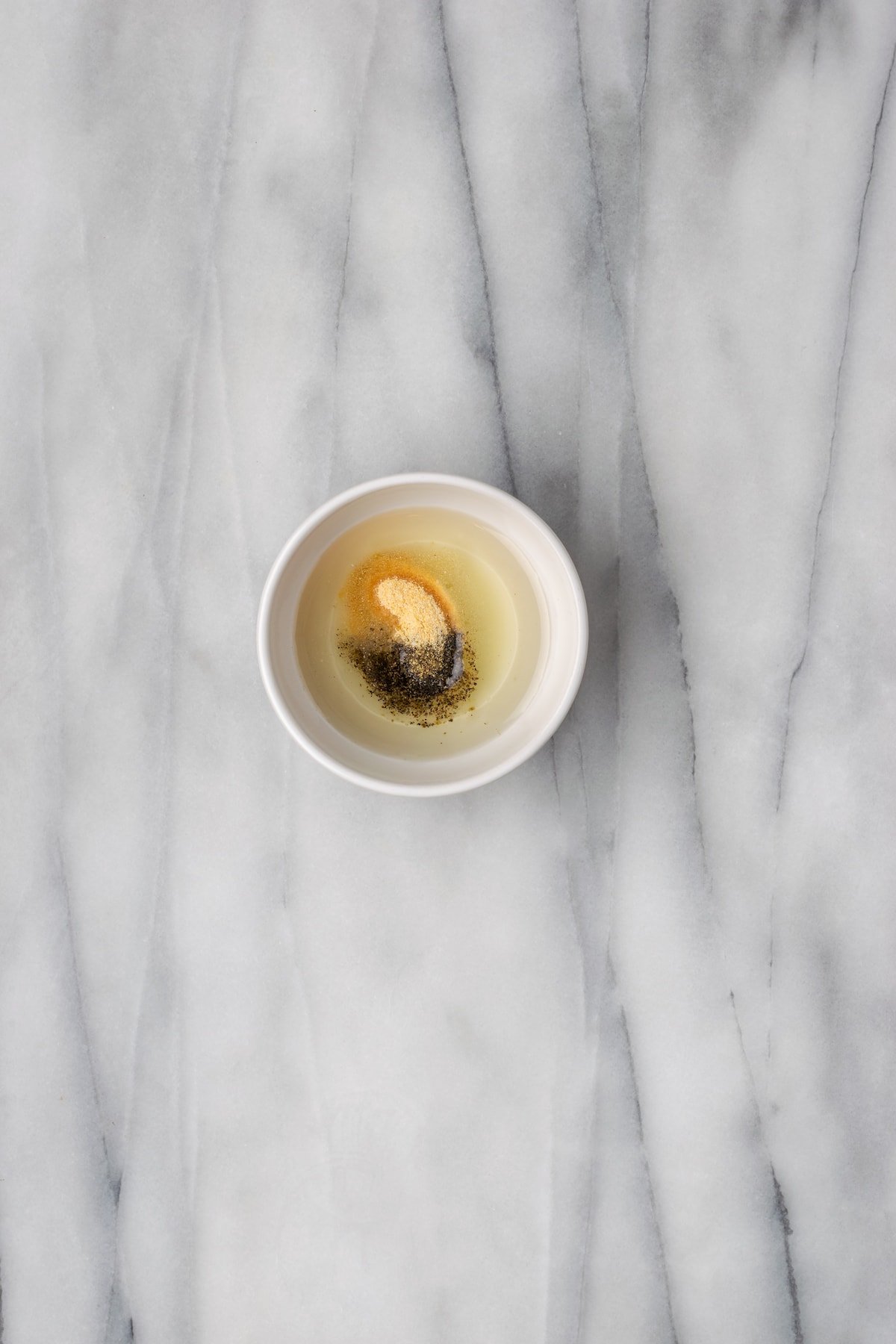 Overhead view of oil and seasoning ingredients in small bowl