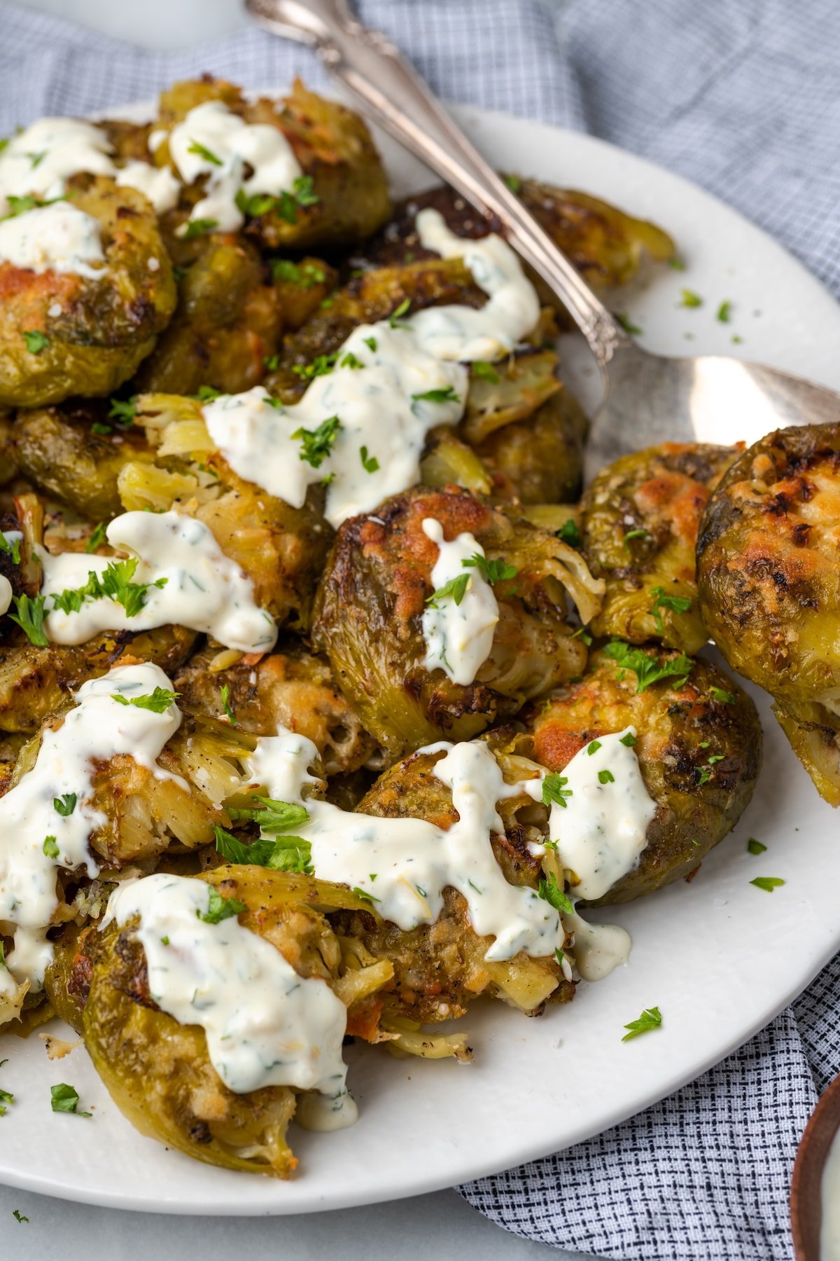 Plate of smashed Brussels sprouts with lemon aioli drizzled over the top