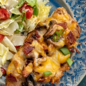 Cheese covered chicken and a salad on blue plate