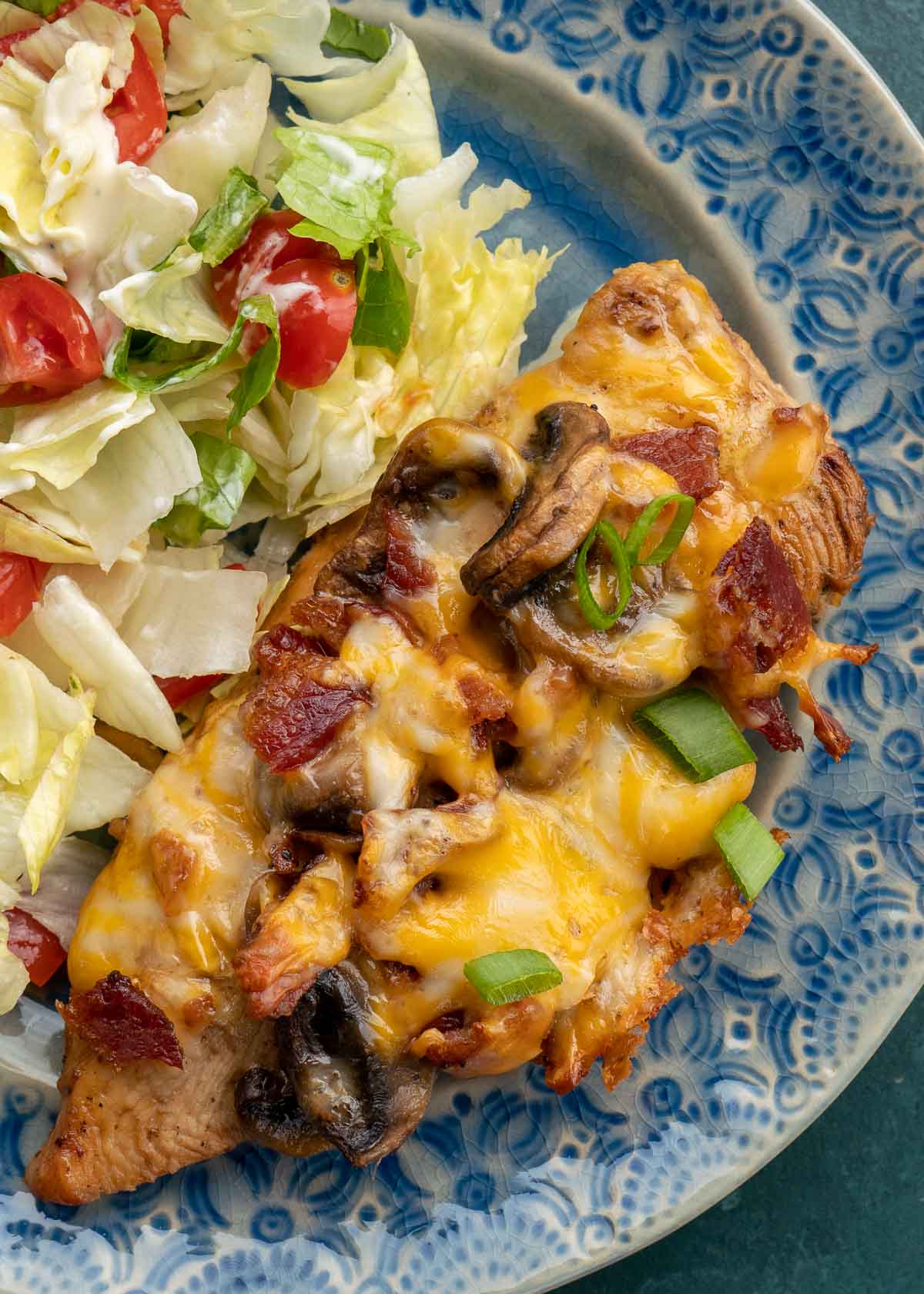 Cheese covered chicken and a salad on blue plate