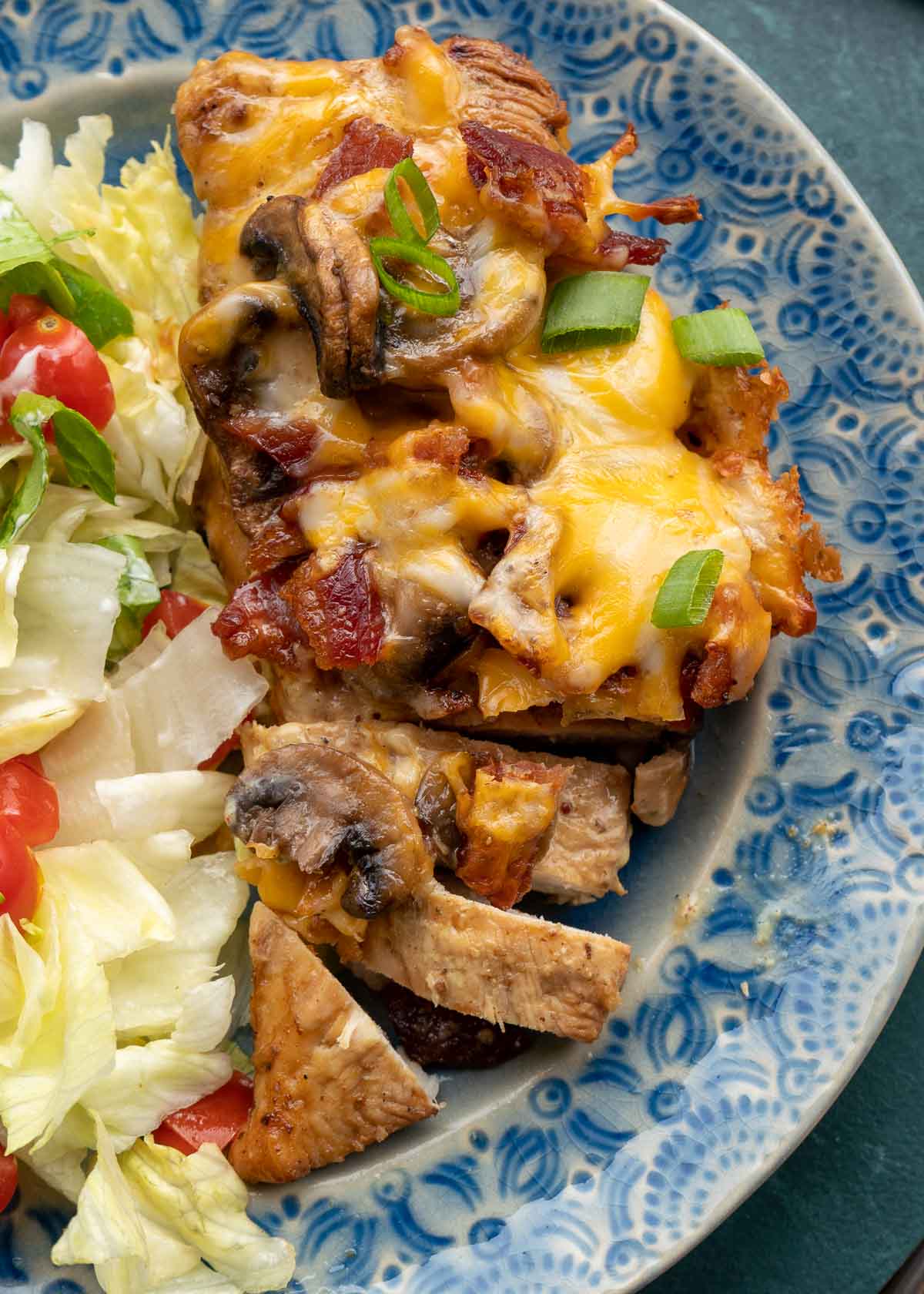 Cheesy chicken and a salad on blue plate