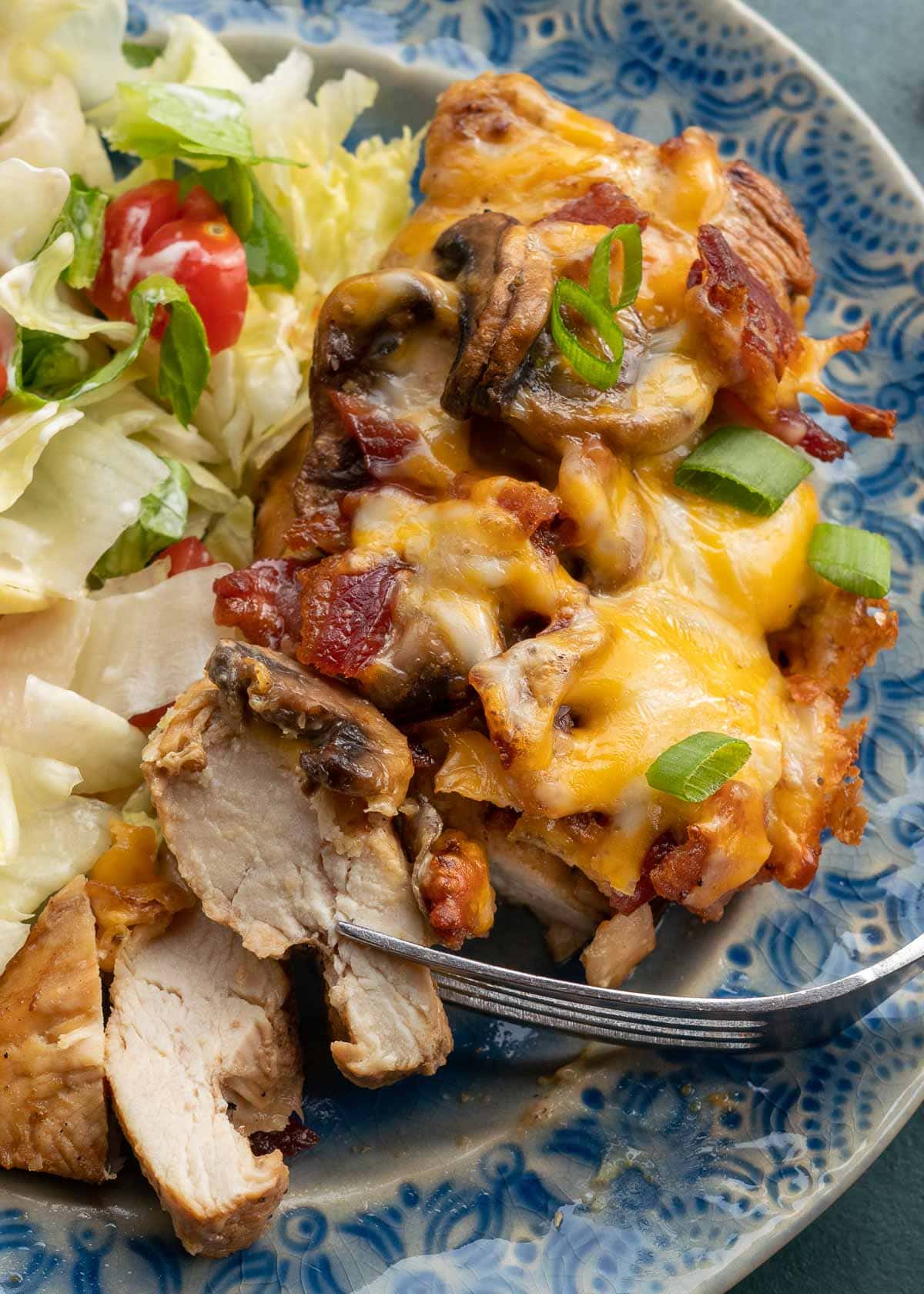 Cheesy chicken and a salad on blue plate