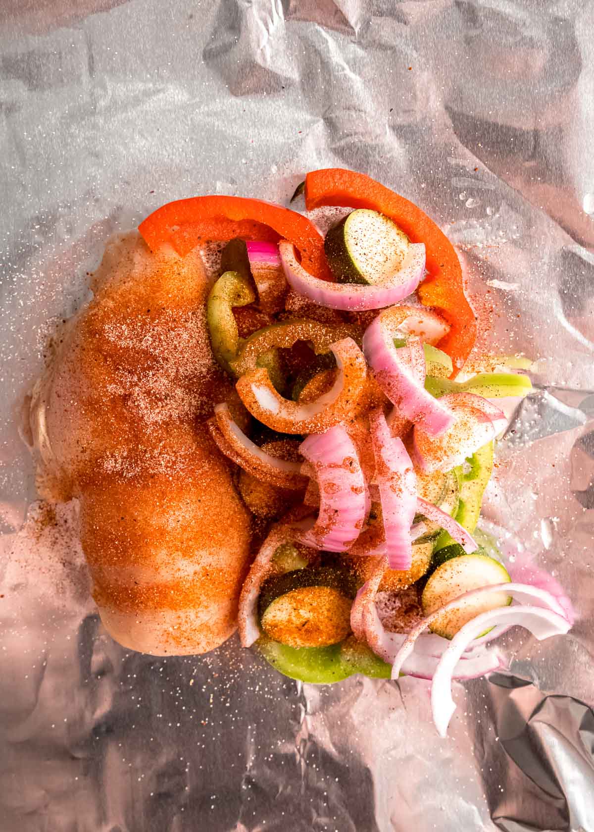 BBQ chicken, vegetables and seasoning in foil