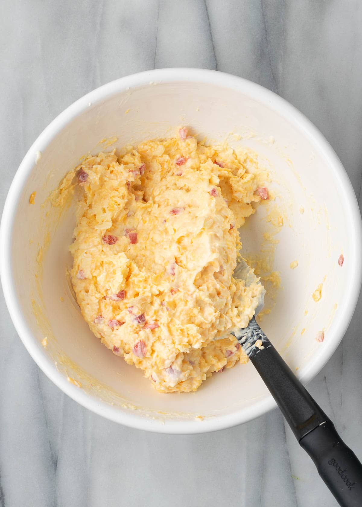 Pimento cheese ingredients being mixed in white mixing bowl