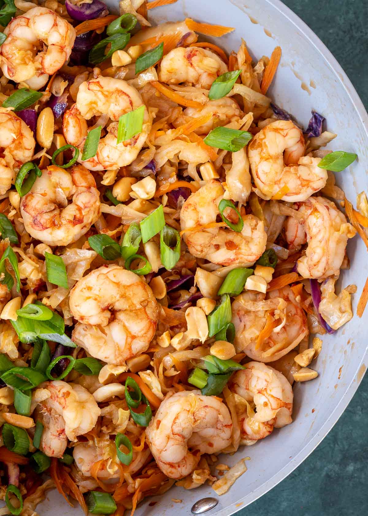 A pan of shrimp stir fry topped with scallions