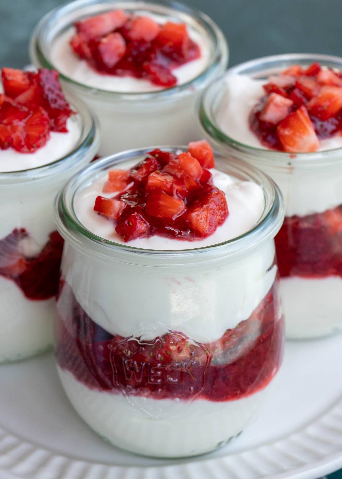 These cute Strawberry Cheesecake Jars are a decadent no-bake dessert! Sweet and creamy vanilla cheesecake is layered with homemade strawberry sauce and fresh berries for the perfect treat!