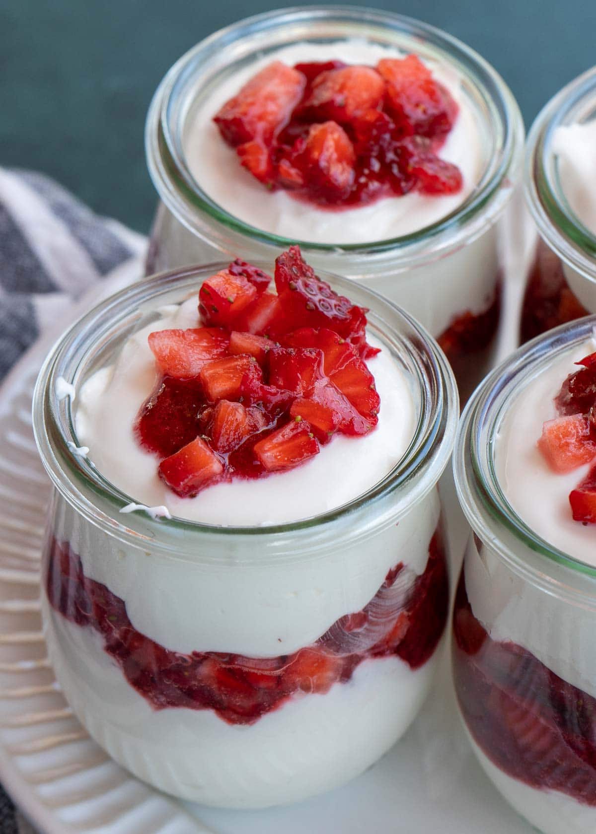 These cute Strawberry Cheesecake Jars are a decadent no-bake dessert! Sweet and creamy vanilla cheesecake is layered with homemade strawberry sauce and fresh berries for the perfect treat!