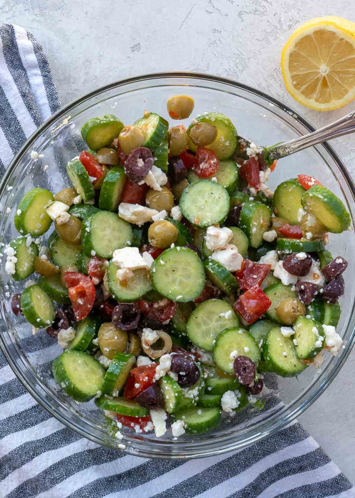 Overhead view of cucumber salad in glass bowl with spoon