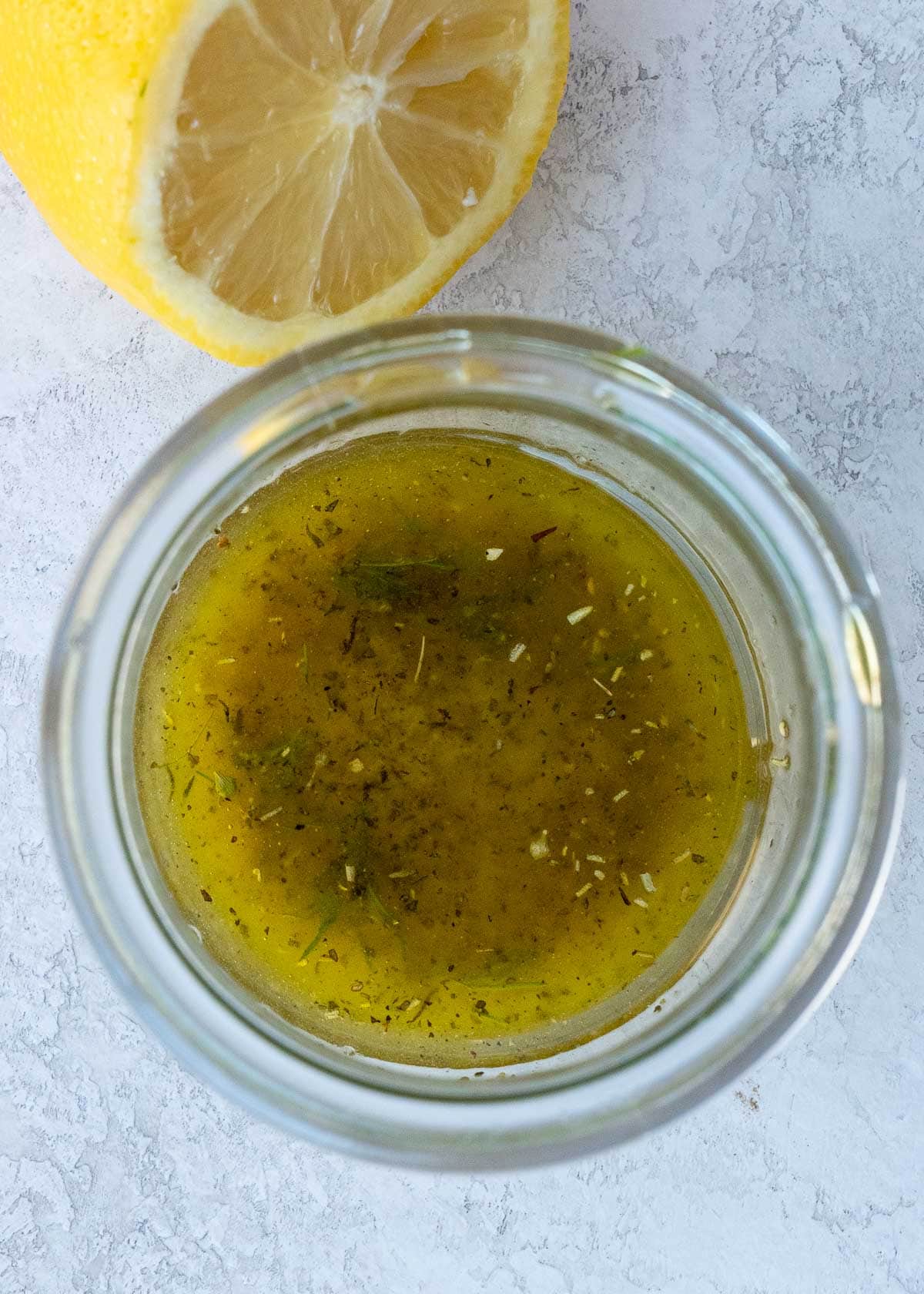 Overhead view of dressing in jar next to lemon half