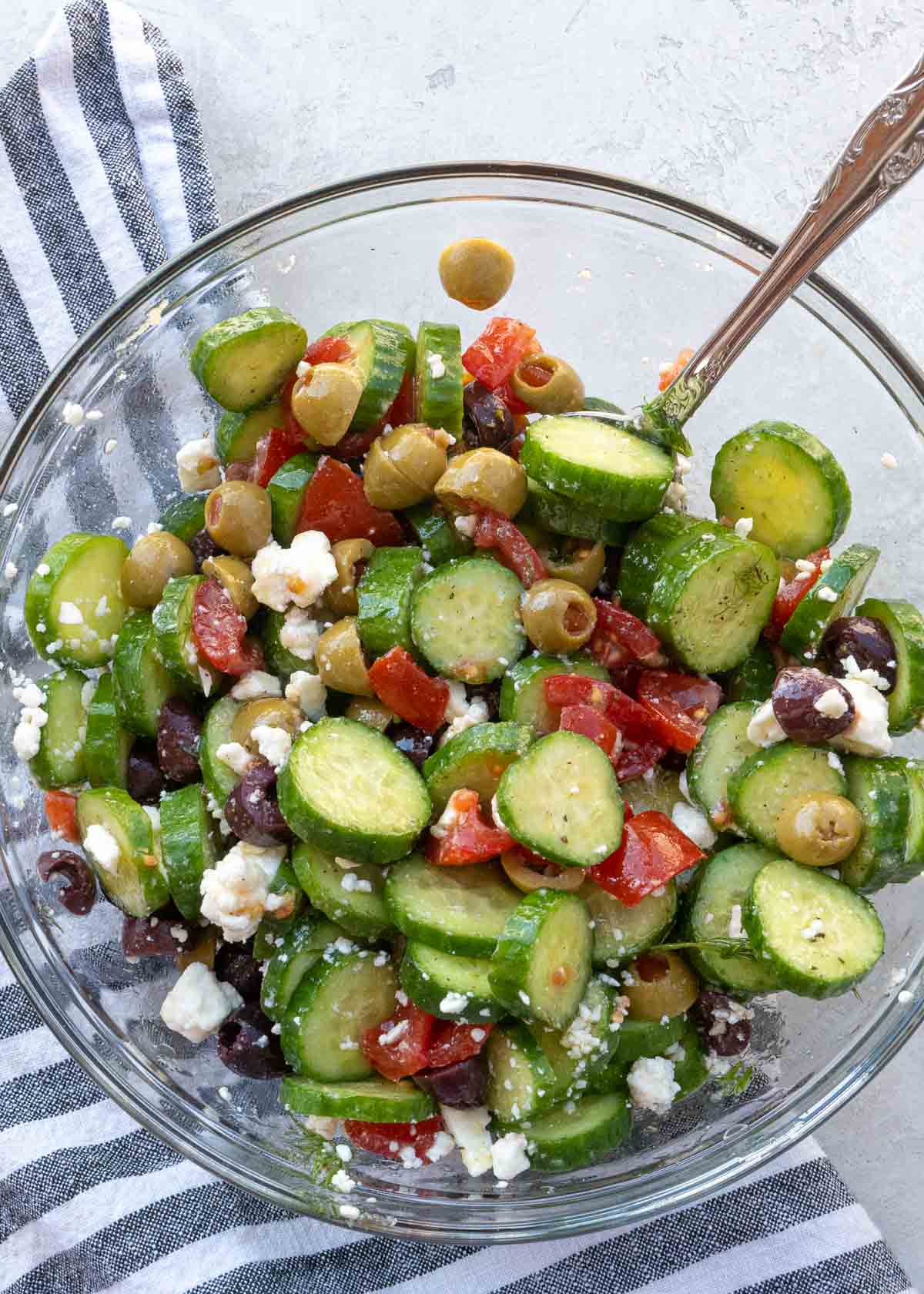 Overhead view of cucumber salad in glass bowl with spoon