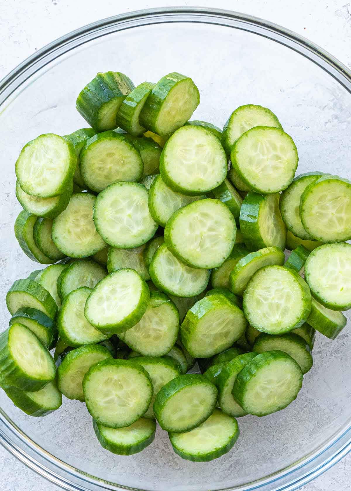 Overhead view of sliced cucumbers in a glass bowl